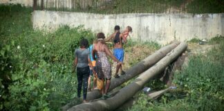 Cancino Adentro cruza sobre dos troncos mientras el puente prometido por Dio Astacio sigue sin llegar